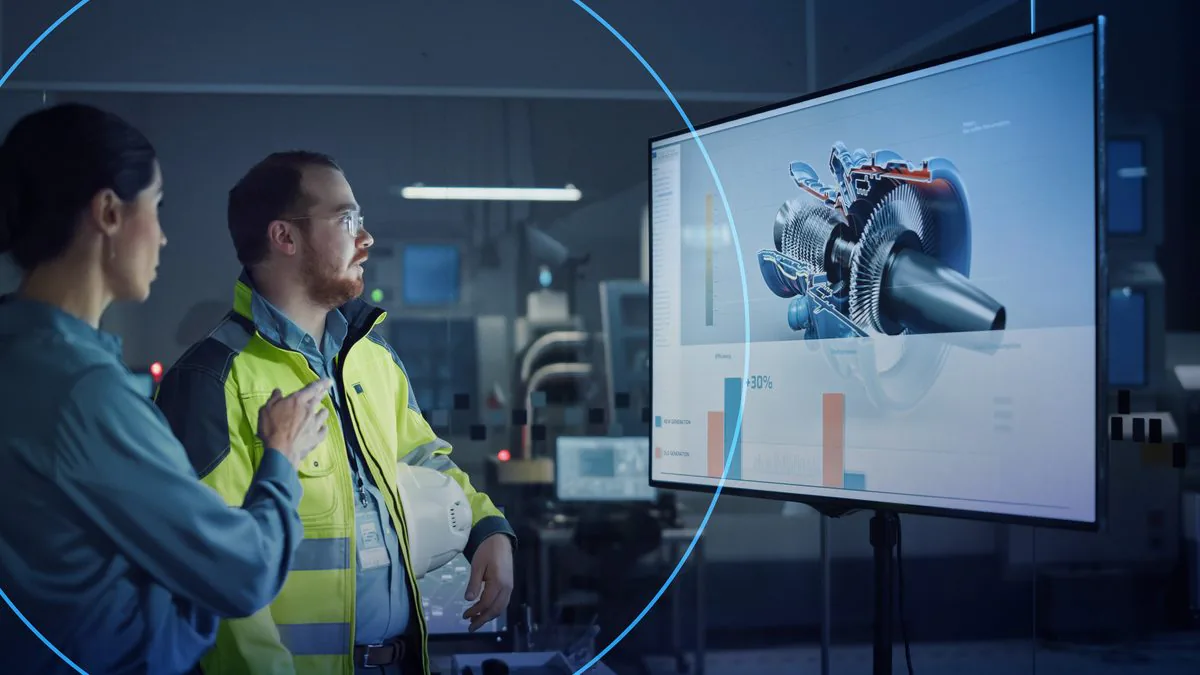 Two engineers reviewing options on a screen in a factory